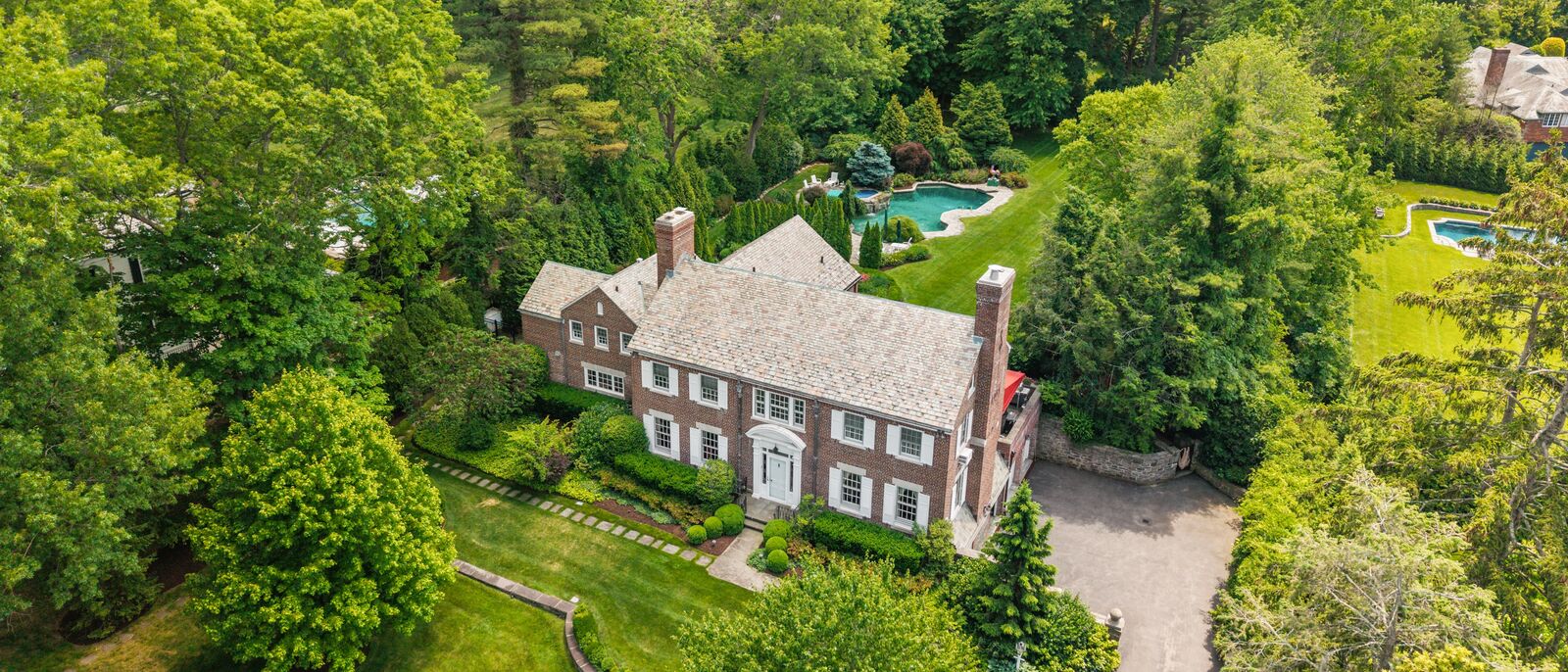 Aerial view of the brick Georgian at 21 Dolma Road, Scarsdale, with its pool and mature grounds