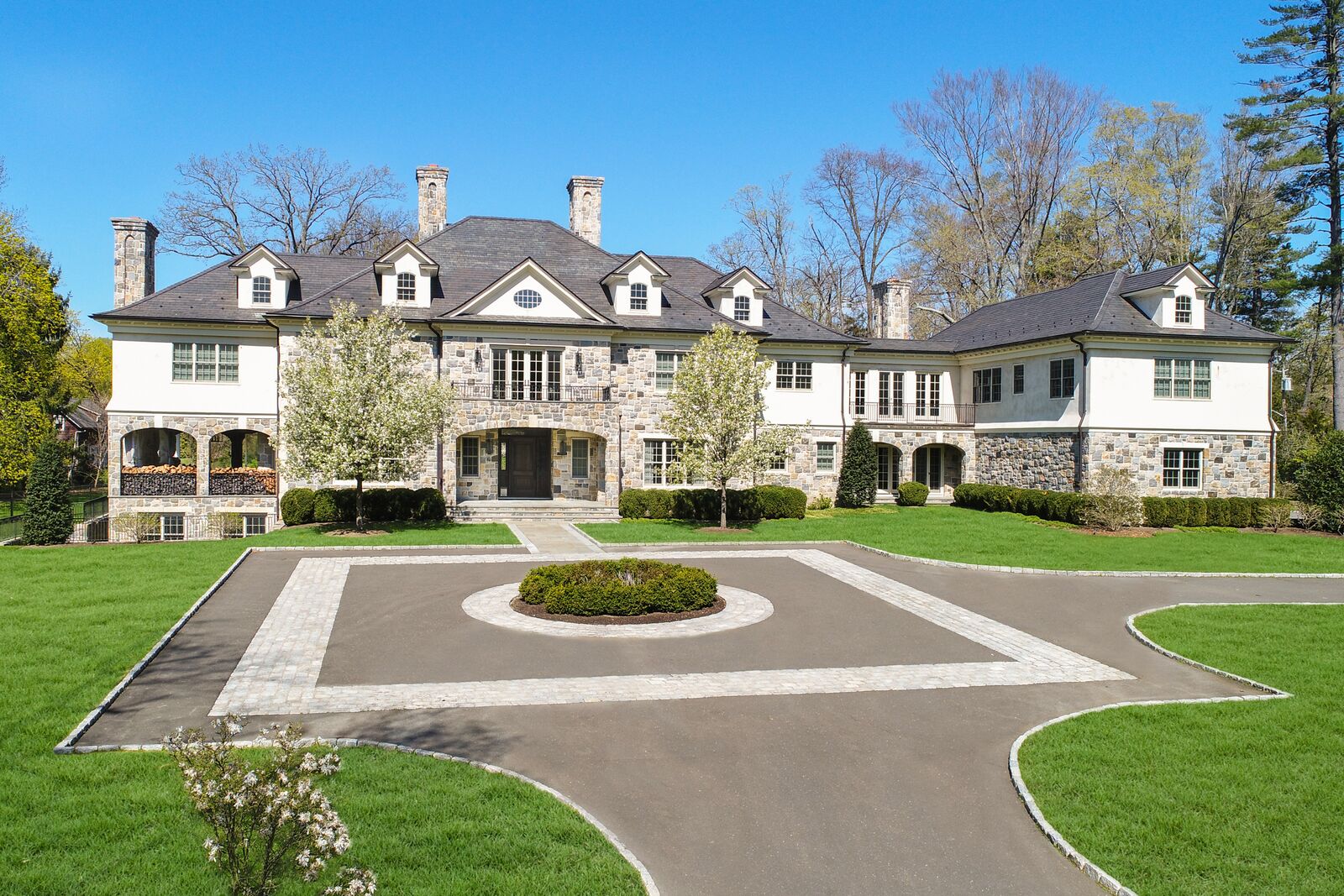 Stone and stucco manor at 1 Duck Pond Road, Scarsdale, behind its formal motor court